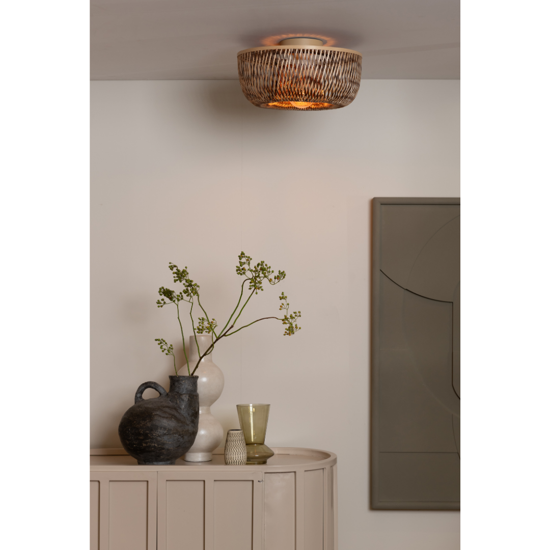 Ein Bild aus dem Taiga Store von taiga.green. In einem gemütlichen Zimmer stehen die Deckenlampe Barbados Bambus/Halbrundschirm ø35xh.15cm, ein beiger Schrank mit einem schwarzen Krug mit grünen Zweigen, eine weiße Vase, zwei kleine Gläser und abstrakte Wandkunst in gedeckten Tönen. Jetzt bestellen im Eco Shop von www.taiga.green. Hier nachhaltig einkaufen mit dem Taiga Eco Rating