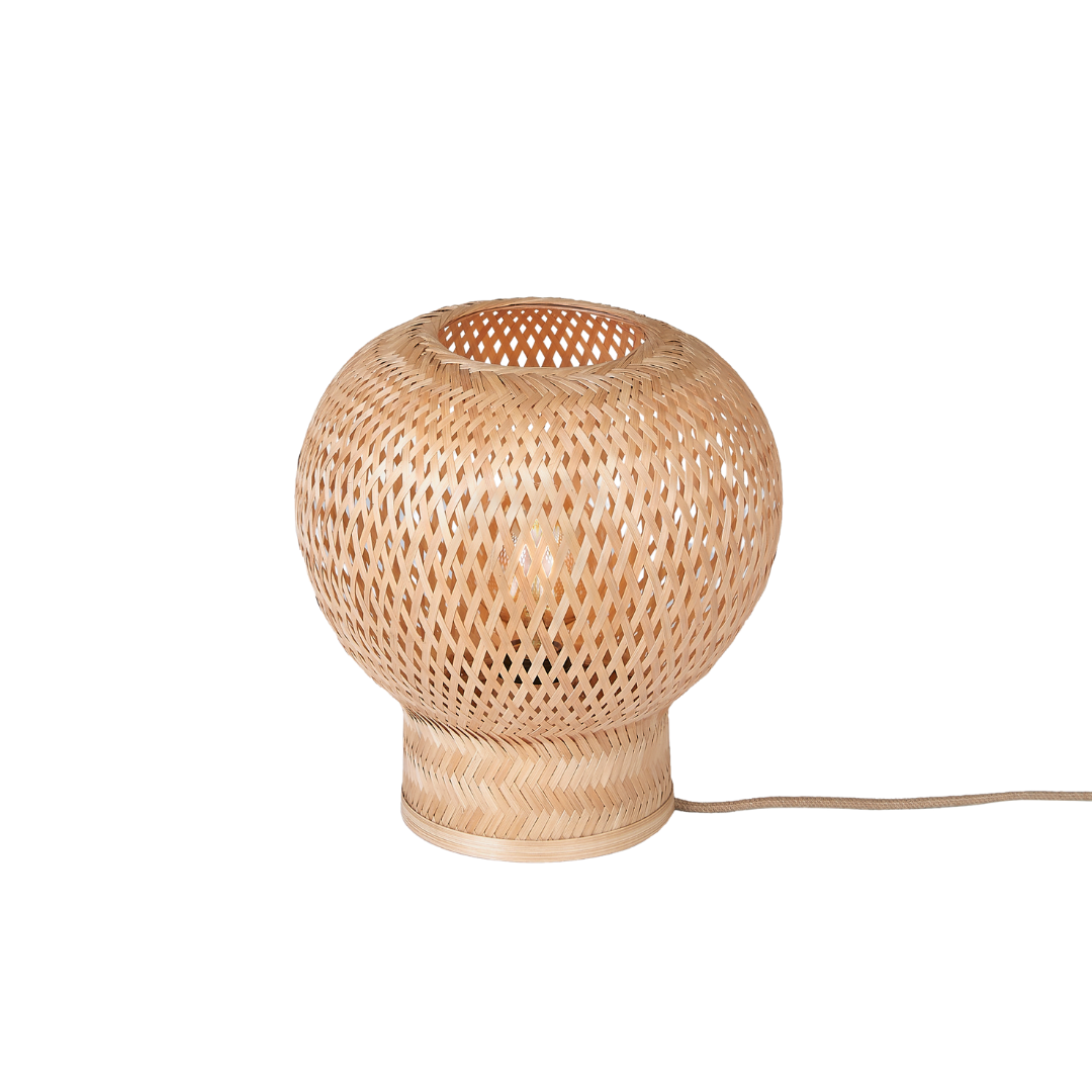 Ein Bild aus dem Taiga Store von taiga.green. Die Tischlampe Barbados Bambus/Globe ø25xh.27cm ist eine runde, geflochtene Rattan-Tischlampe mit breitem Sockel und offenem Flechtmuster, dargestellt auf einem schlichten weißen Hintergrund. Vom Sockel geht ein elektrisches Kabel aus. Jetzt bestellen im Eco Shop von www.taiga.green. Hier nachhaltig einkaufen mit dem Taiga Eco Rating