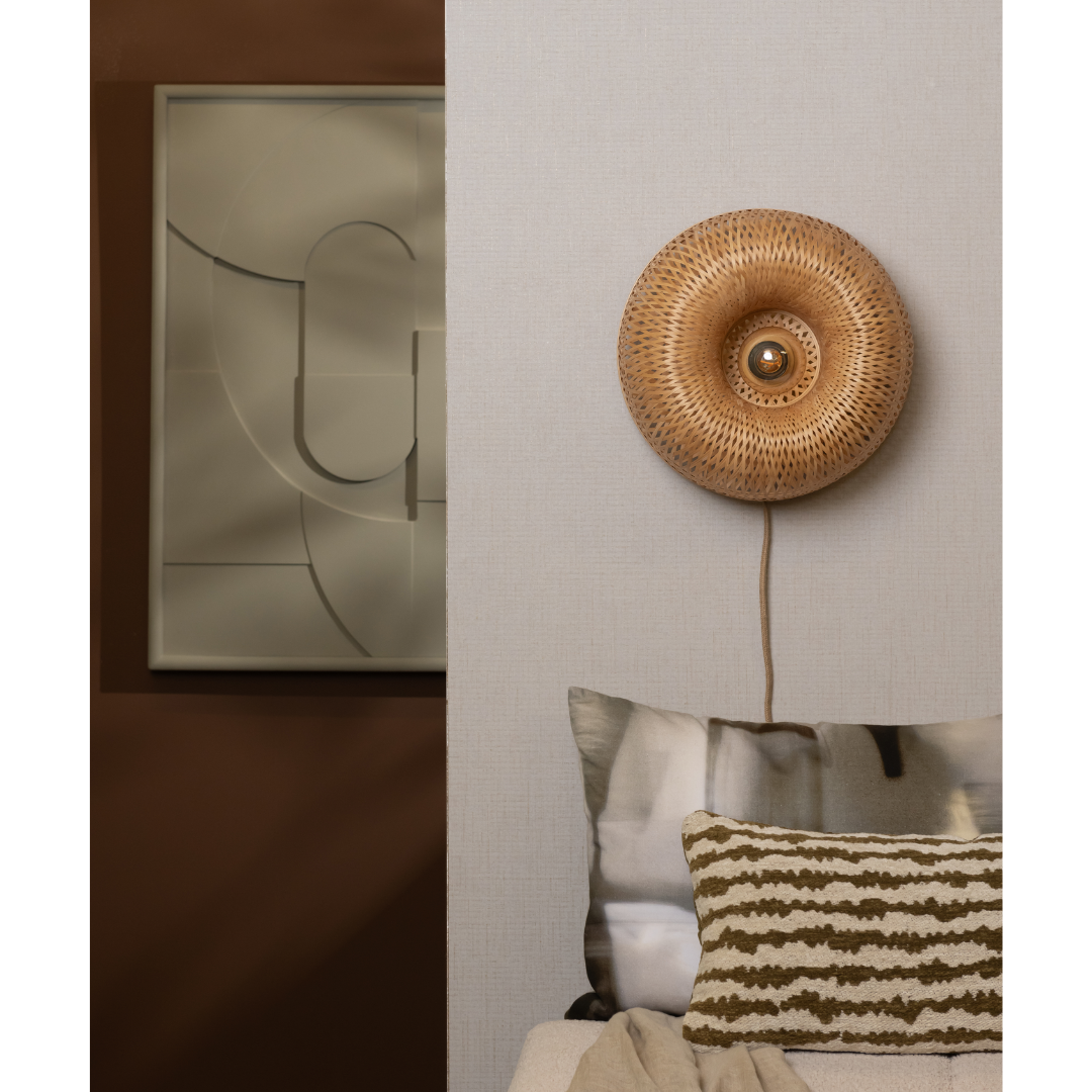 Ein Bild aus dem Taiga Store von taiga.green. Eine moderne Schlafzimmerecke mit einem abstrakten Wandbild, einer geflochtenen, runden Wandlampe und einem Bett mit neutral getönten Kissen und einem strukturierten Kissen. Die Einrichtung besteht aus einer Mischung aus warmen Braun- und Beigetönen. Jetzt bestellen im Eco Shop von www.taiga.green. Hier nachhaltig einkaufen mit dem Taiga Eco Rating