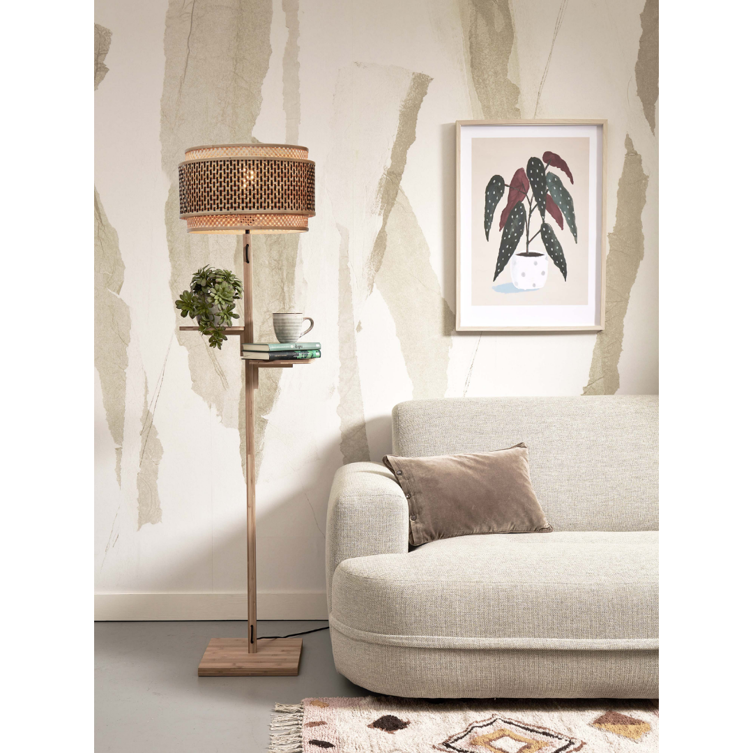 Ein Bild aus dem Taiga Store von taiga.green. Ein minimalistisches Wohnzimmer mit einem hellgrauen Sofa, einem braunen Kissen, einer hölzernen Stehlampe mit einem runden gewebten Schirm und einem kleinen Regal mit einer Pflanze und Büchern. An der Wand befinden sich abstrakte Tapeten und gerahmte Pflanzenkunst. Jetzt bestellen im Eco Shop von www.taiga.green. Hier nachhaltig einkaufen mit dem Taiga Eco Rating