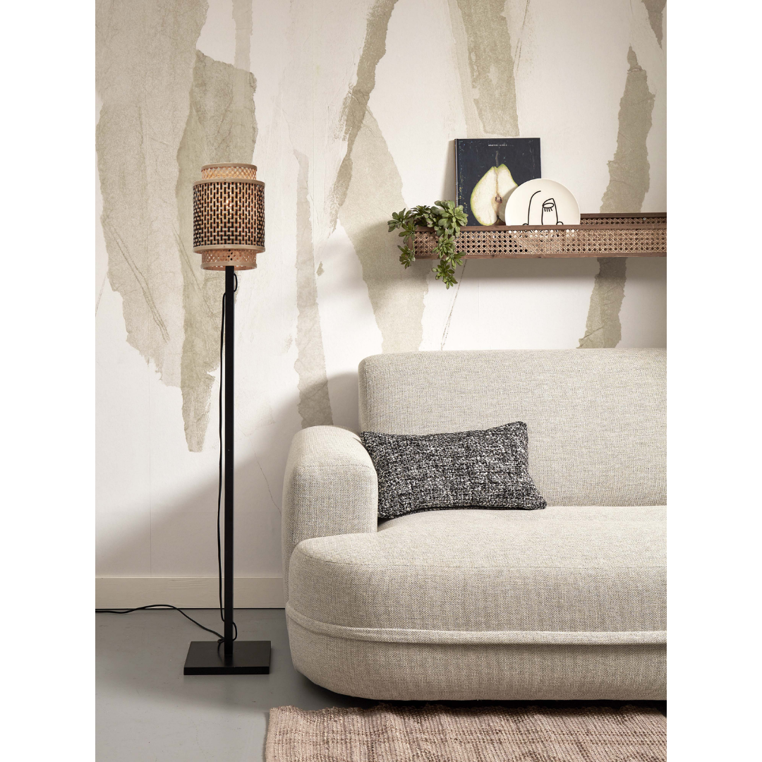 Ein Bild aus dem Taiga Store von taiga.green. Ein modernes Wohnzimmer mit einem hellgrauen Sofa, einem strukturierten schwarz-weißen Kissen, einer schwarzen Stehlampe mit gewebtem Schirm, einem beigen Teppich und einem Wandregal mit Büchern und Dekorationsgegenständen vor einer gemusterten Wand. Jetzt bestellen bei www.taiga.green.