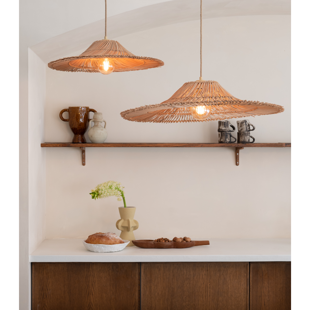 Ein Bild aus dem Taiga Store von taiga.green. Eine minimalistische Küchenszene mit zwei geflochtenen Pendelleuchten, einem schwebenden Regal mit Töpferwaren und Tassen sowie einer Theke, auf der eine Vase mit weißen Blumen, ein Laib Brot und Holzteller mit Snacks stehen. Jetzt bestellen im Eco Shop von www.taiga.green. Hier nachhaltig einkaufen mit dem Taiga Eco Rating