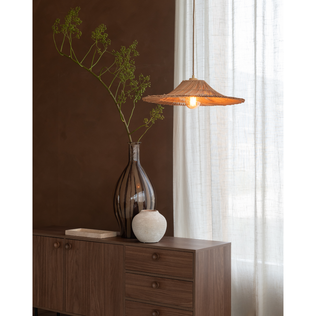 Ein Bild aus dem Taiga Store von taiga.green. Ein hölzernes Sideboard mit zwei dekorativen Vasen - eine groß mit grünen Zweigen, eine klein und weiß - steht neben einem Fenster mit transparenten Vorhängen, das von einer hängenden Rattanlampe beleuchtet wird. Jetzt bestellen im Eco Shop von www.taiga.green. Hier nachhaltig einkaufen mit dem Taiga Eco Rating