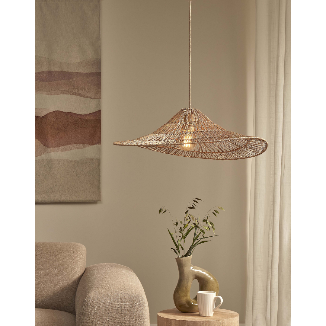 Ein Bild aus dem Taiga Store von taiga.green. Ein gemütliches Wohnzimmer mit einem beigen Sessel, einem runden Beistelltisch aus Holz, auf dem eine moderne Vase mit grünen Zweigen steht, einer weißen Tasse, einer geflochtenen Pendelleuchte, abstrakter Wandkunst und transparenten Vorhängen. Jetzt bestellen im Eco Shop von www.taiga.green. Hier nachhaltig einkaufen mit dem Taiga Eco Rating
