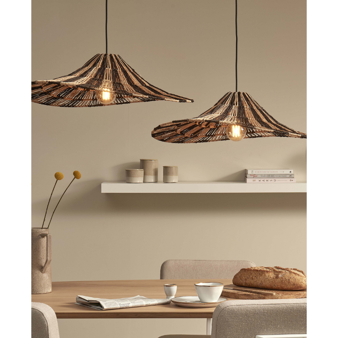 Ein Bild aus dem Taiga Store von taiga.green. Ein Essbereich mit einem Holztisch, beigen Stühlen und zwei darüber hängenden geflochtenen Pendelleuchten. Auf dem Tisch stehen ein Laib Brot, eine Tasse und eine Vase mit gelben Blumen. An der Wand befindet sich ein schwebendes Regal mit Büchern und Keramiken. Jetzt bestellen im Eco Shop von www.taiga.green. Hier nachhaltig einkaufen mit dem Taiga Eco Rating