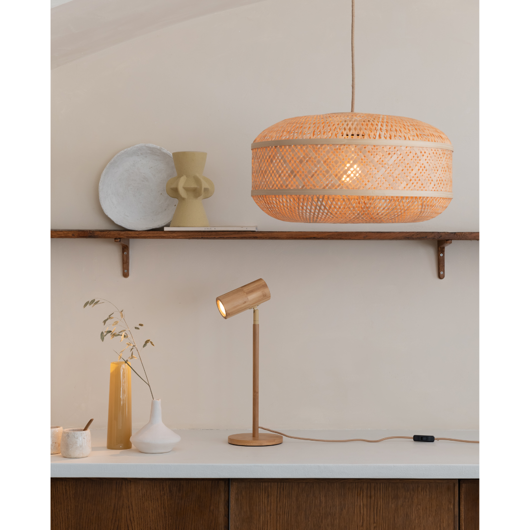 Ein Bild aus dem Taiga Store von taiga.green. Eine minimalistische Innenraumszene mit einer Pendelleuchte aus geflochtenem Rattan, einer Schreibtischlampe aus Holz, Keramikvasen, getrockneten Zweigen in einer Glasvase und dekorativen Tellern auf einem Holzregal vor einer neutralen Wand. Jetzt bestellen im Eco Shop von www.taiga.green. Hier nachhaltig einkaufen mit dem Taiga Eco Rating