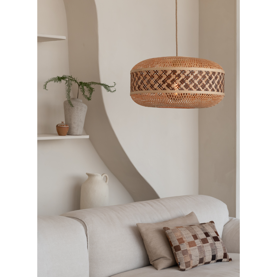 Ein Bild aus dem Taiga Store von taiga.green. Ein modernes, minimalistisches Wohnzimmer mit einem beigen Sofa, gemusterten Kissen, einer Pendelleuchte aus geflochtenem Rattan, Topfpflanzen auf weißen Regalen und neutral getönten Wänden. Jetzt bestellen im Eco Shop von www.taiga.green. Hier nachhaltig einkaufen mit dem Taiga Eco Rating
