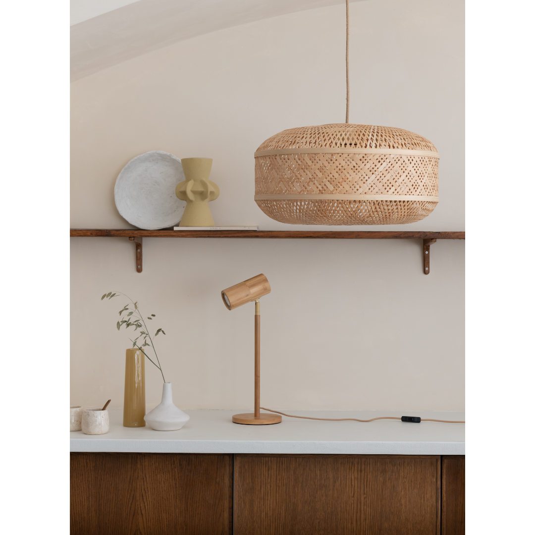 Ein Bild aus dem Taiga Store von taiga.green. Ein minimalistisches Interieur mit einer Rattan-Hängelampe, einer Schreibtischlampe aus Holz und Keramikvasen auf einer weißen Arbeitsplatte. Darüber befindet sich ein Holzregal mit weiteren Keramiken vor einer beigen Wand. Jetzt bestellen im Eco Shop von www.taiga.green. Hier nachhaltig einkaufen mit dem Taiga Eco Rating