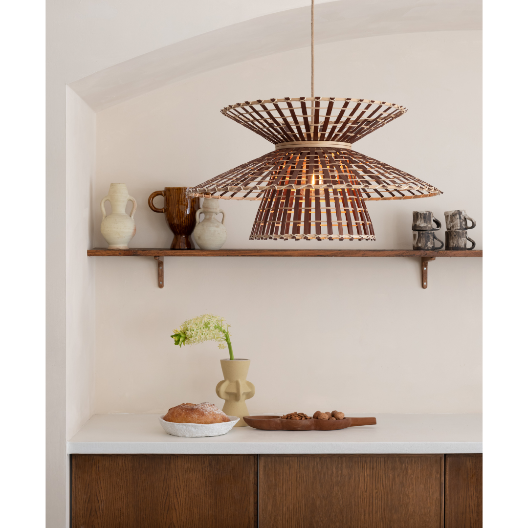 Ein Bild aus dem Taiga Store von taiga.green. Eine moderne Küche mit einer weißen Arbeitsplatte, Holzschränken, einem Brotlaib und einer Vase auf der Arbeitsplatte, einer hölzernen Pendelleuchte und einem Regal mit Keramikvasen und -bechern vor einer hellen Wand. Jetzt bestellen im Eco Shop von www.taiga.green. Hier nachhaltig einkaufen mit dem Taiga Eco Rating