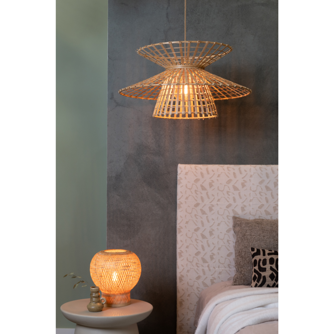 Ein Bild aus dem Taiga Store von taiga.green. In einem gemütlichen Schlafzimmer hängen ein geflochtener Lampenschirm von der Decke und eine passende Rattan-Tischlampe auf einem kleinen runden Tisch neben einem Bett mit gemustertem Kopfteil und neutraler Bettwäsche. Jetzt bestellen im Eco Shop von www.taiga.green. Hier nachhaltig einkaufen mit dem Taiga Eco Rating