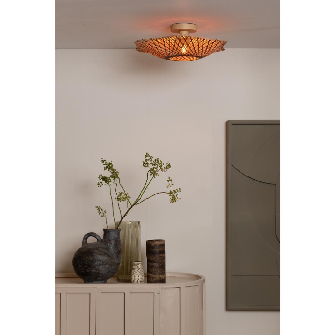 Ein Bild aus dem Taiga Store von taiga.green. Die Deckenlampe Madura Bambus/Schirm ø44x12cm S wirft ein warmes Licht über einen beigen Konsolentisch mit Keramikvasen - eine davon mit grünen Zweigen - vor einer cremefarbenen Wand mit moderner abstrakter Kunst. Jetzt bestellen im Eco Shop von www.taiga.green. Hier nachhaltig einkaufen mit dem Taiga Eco Rating