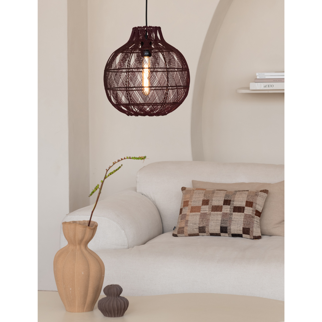 Ein Bild aus dem Taiga Store von taiga.green. Ein gemütliches Wohnzimmer mit einem weißen Sofa, einem gemusterten Kissen und der darüber hängenden Hängelampe Mendoza Bambus/Schirm ø35xh.35cm S. Eine dekorative Vase mit einem einzelnen Zweig steht auf einem kleinen Tisch, im Hintergrund ein Regal mit Büchern. Jetzt bestellen im Eco Shop von www.taiga.green. Hier nachhaltig einkaufen mit dem Taiga Eco Rating