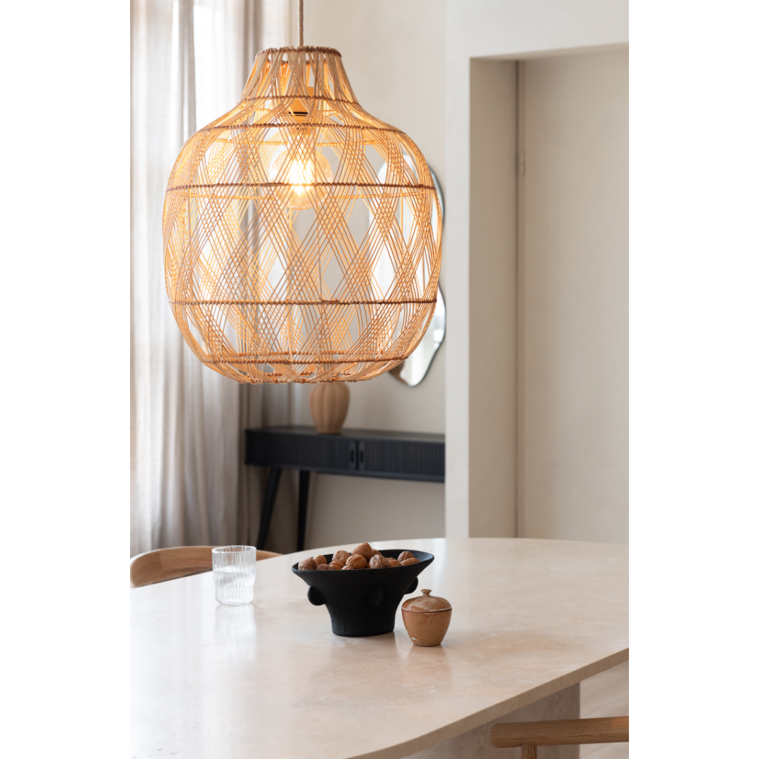Ein Bild aus dem Taiga Store von taiga.green. Die Hängelampe Mendoza Bambus/Schirm ø40xh.50cm L hängt über einem hellen Tisch mit einem Glas Wasser, einer schwarzen Nussschale und einem kleinen Behälter, während das natürliche Licht durch die Vorhänge in diesem minimalistischen Esszimmer fällt. Jetzt bestellen im Eco Shop von www.taiga.green. Hier nachhaltig einkaufen mit dem Taiga Eco Rating