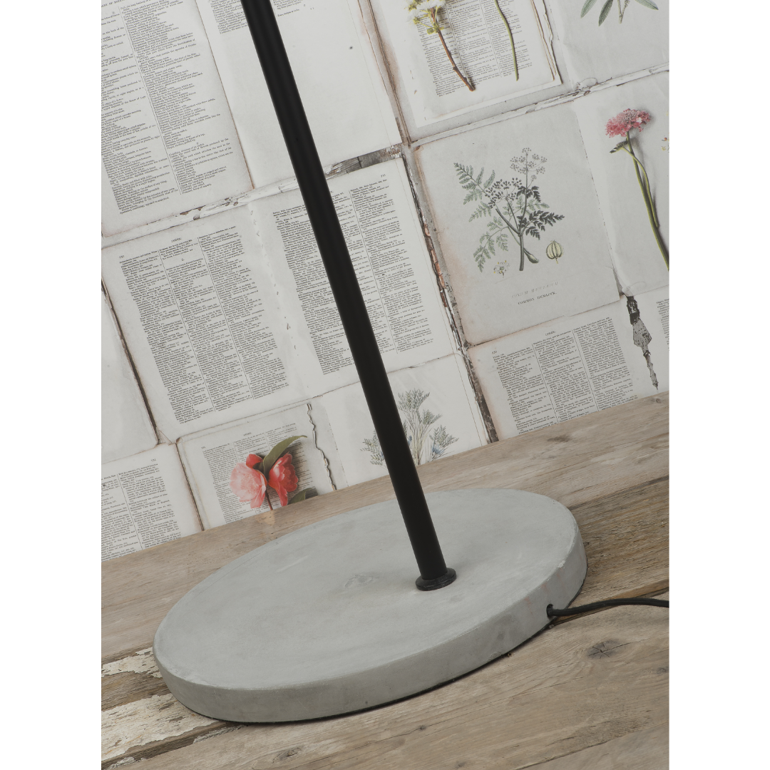 Ein Bild aus dem Taiga Store von taiga.green. Ein runder Betonsockel steht auf einer Holzfläche. Dahinter ist die Wand mit Buchseiten und botanischen Illustrationen bedeckt. Vom Sockel geht eine schwarze Schnur aus. Jetzt bestellen im Eco Shop von www.taiga.green. Hier nachhaltig einkaufen mit dem Taiga Eco Rating