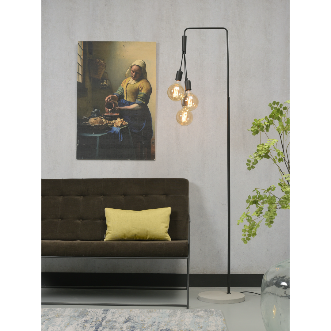 Ein Bild aus dem Taiga Store von taiga.green. Ein modernes Wohnzimmer mit einem braunen Sofa, gelben Kissen, einer Stehlampe mit freiliegenden Glühbirnen, einer Pflanze in einer Glasvase und einem Wandgemälde von Vermeers Die Milchmagd. Jetzt bestellen im Eco Shop von www.taiga.green. Hier nachhaltig einkaufen mit dem Taiga Eco Rating