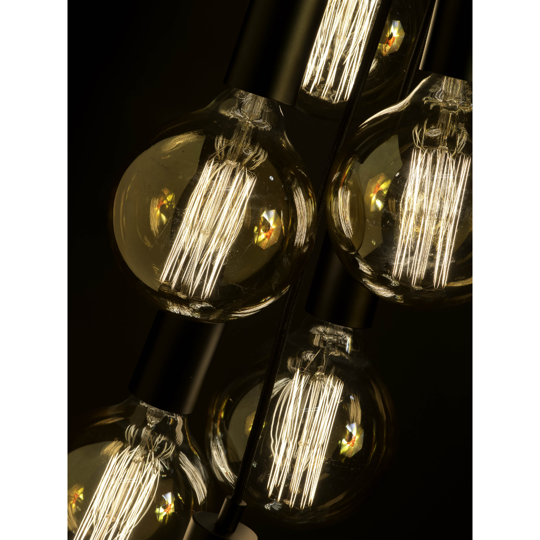 Ein Bild aus dem Taiga Store von taiga.green. Nahaufnahme von mehreren beleuchteten Edison-Glühbirnen im Vintage-Stil mit sichtbaren Glühfäden, die dicht nebeneinander vor einem dunklen Hintergrund angeordnet sind. Jetzt bestellen im Eco Shop von www.taiga.green. Hier nachhaltig einkaufen mit dem Taiga Eco Rating