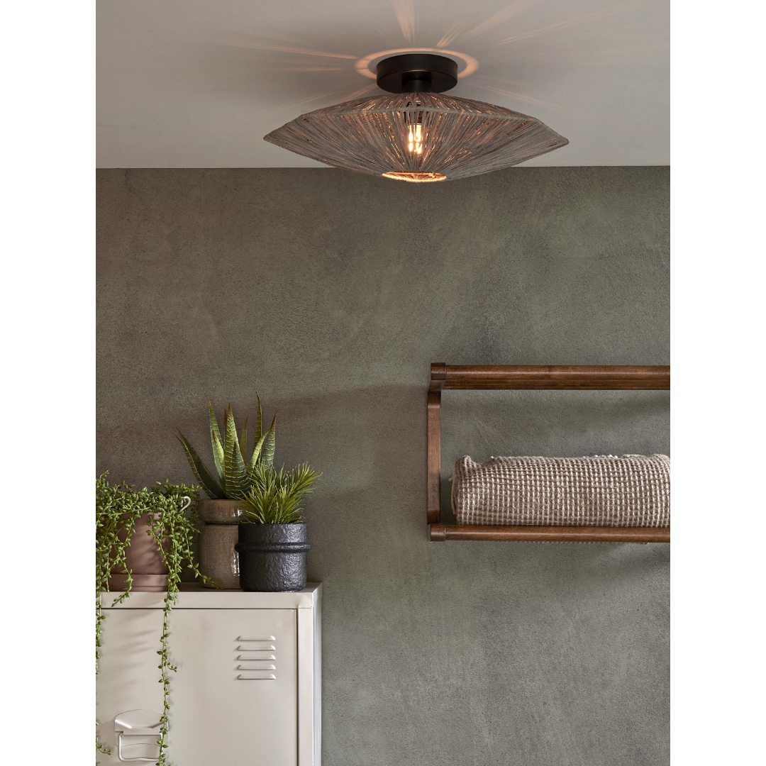 Ein Bild aus dem Taiga Store von taiga.green. Eine moderne Deckenleuchte mit einem geflochtenen Schirm beleuchtet einen minimalistischen Raum mit grünen Wänden, einem weißen Metallschrank mit Topfpflanzen und einem Holzregal mit einem aufgerollten Handtuch. Jetzt bestellen im Eco Shop von www.taiga.green. Hier nachhaltig einkaufen mit dem Taiga Eco Rating