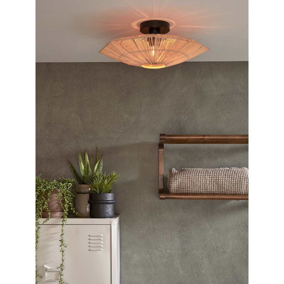 Ein Bild aus dem Taiga Store von taiga.green. Eine Deckenleuchte aus Rattan leuchtet warm in einem minimalistischen Raum mit einer grau strukturierten Wand, einem weißen Metallschrank mit Topfpflanzen und einem Holzregal mit einem gerollten Handtuch. Jetzt bestellen im Eco Shop von www.taiga.green. Hier nachhaltig einkaufen mit dem Taiga Eco Rating