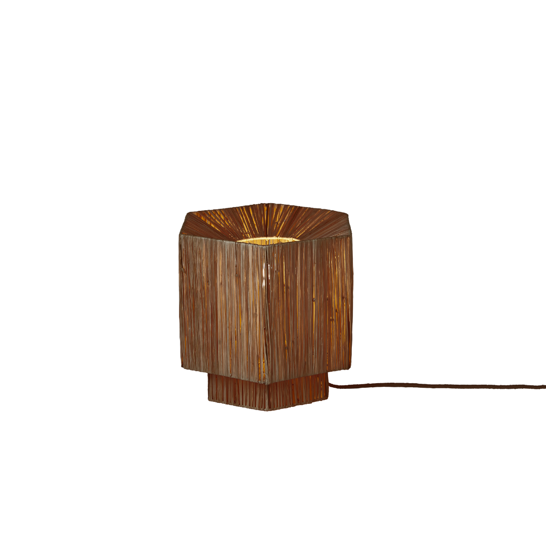 Ein Bild aus dem Taiga Store von taiga.green. Sechseckige Tischleuchte mit Holzlattenkonstruktion, die warmes Licht aus dem Inneren abgibt. Die Lampe hat ein natürliches, rustikales Aussehen und ein freiliegendes Kabel auf der rechten Seite. Jetzt bestellen im Eco Shop von www.taiga.green. Hier nachhaltig einkaufen mit dem Taiga Eco Rating