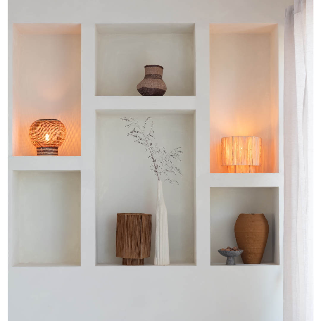 Ein Bild aus dem Taiga Store von taiga.green. Auf einem eingebauten weißen Wandregal stehen dekorative Vasen, geflochtene Körbe, zwei beleuchtete Lampen und eine hohe weiße Vase mit getrockneten Zweigen. Sanftes natürliches und warmes Lampenlicht schaffen eine gemütliche Atmosphäre. Jetzt bestellen im Eco Shop von www.taiga.green. Hier nachhaltig einkaufen mit dem Taiga Eco Rating