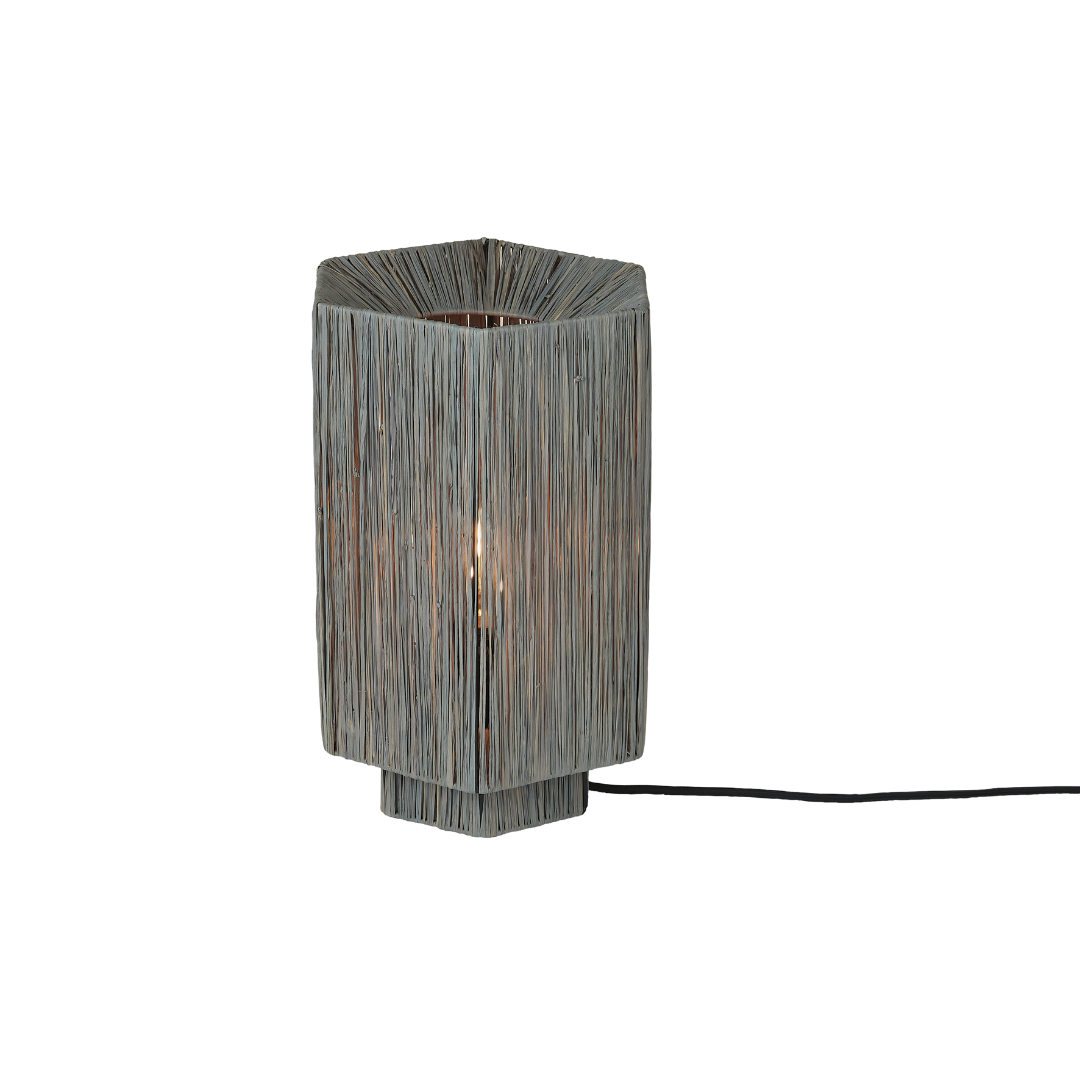 Ein Bild aus dem Taiga Store von taiga.green. Eine moderne, sechseckige Tischleuchte mit einem vertikalen Drahtgestell in grauer Ausführung, das eine Glühbirne im Inneren offenbart. Die Lampe steht auf einem passenden sechseckigen Sockel und hat ein sichtbares schwarzes Stromkabel. Jetzt bestellen im Eco Shop von www.taiga.green. Hier nachhaltig einkaufen mit dem Taiga Eco Rating