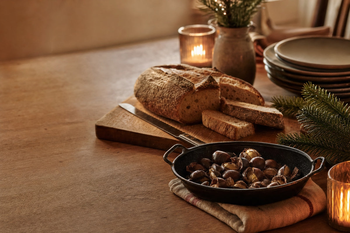 Brot auf dem Holzbrett und Maronen in der Eisenpfanne auf dem festlichen Tisch