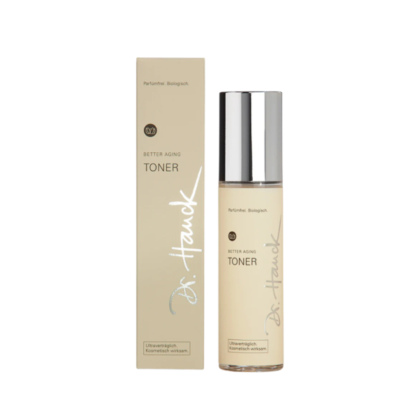 Ein Bild aus dem Taiga Store von taiga.green. Eine beigefarbene Flasche Dr. Hauck Better Aging Toner mit silbernem Verschluss ist neben der dazugehörigen rechteckigen Schachtel abgebildet, die beide mit dem Produktnamen und dem Branding in weißer und goldener Schrift versehen sind. Jetzt bestellen im Eco Shop von www.taiga.green. Hier nachhaltig einkaufen mit dem Taiga Eco Rating