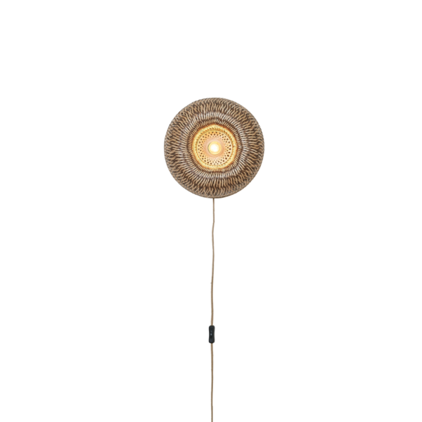 Ein Bild aus dem Taiga Store von taiga.green. Eine runde, geflochtene Wandlampe mit einer leuchtenden Glühbirne in der Mitte und einer Schnur, die gerade nach unten hängt, vor einem schlichten schwarzen Hintergrund. Jetzt bestellen im Eco Shop von www.taiga.green. Hier nachhaltig einkaufen mit dem Taiga Eco Rating