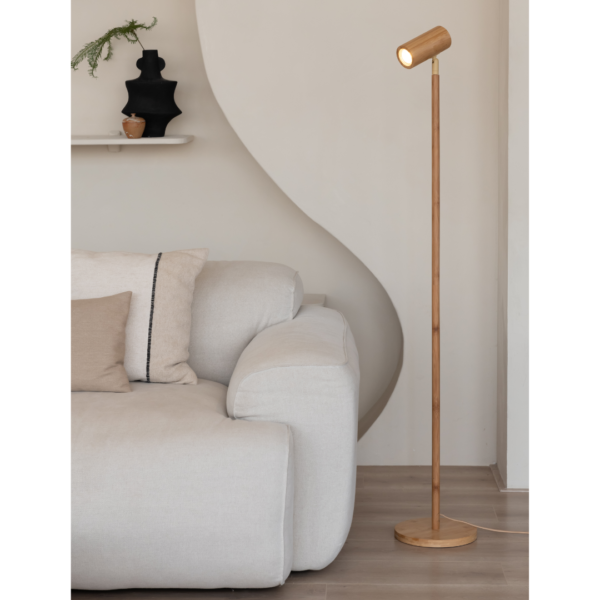 Ein Bild aus dem Taiga Store von taiga.green. Ein modernes Wohnzimmer mit einem hellen Sofa, beigen und hellbraunen Kissen, einer Stehlampe aus Holz und einer weißen Wand mit einem kleinen Regal mit einer schwarzen Vase und einer kleinen Pflanze. Jetzt bestellen im Eco Shop von www.taiga.green. Hier nachhaltig einkaufen mit dem Taiga Eco Rating
