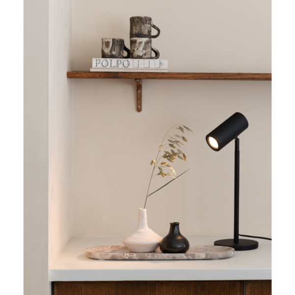 Ein Bild aus dem Taiga Store von taiga.green. Eine minimalistische Einrichtung mit einer schwarzen Schreibtischlampe, zwei Vasen auf einem Tablett und getrocknetem Gras auf einer weißen Fläche. Darüber stehen in einem Holzregal rustikale Tassen und ein POLPO-Buch vor einer beigen Wand. Jetzt bestellen im Eco Shop von www.taiga.green. Hier nachhaltig einkaufen mit dem Taiga Eco Rating