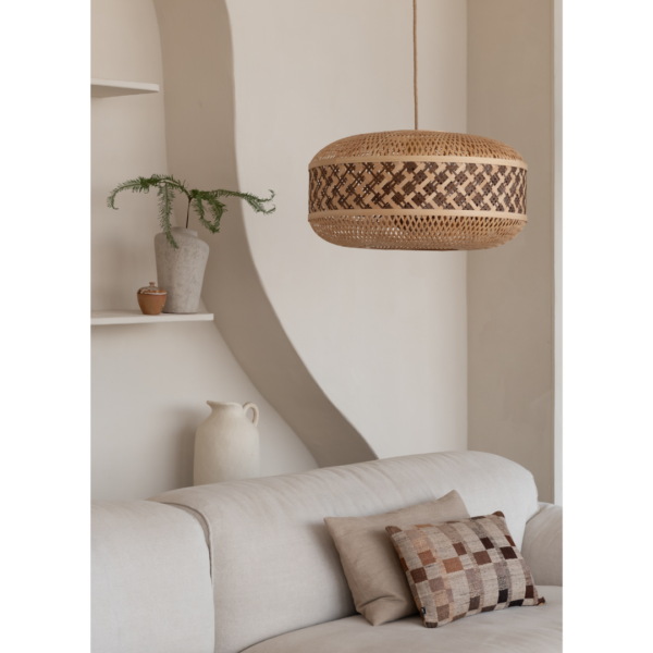 Ein Bild aus dem Taiga Store von taiga.green. Ein in neutralen Tönen gehaltenes Wohnzimmer mit einem beigen Sofa, einem Patchwork-Kissen, einer Pendelleuchte aus geflochtenem Rattan, einem weißen Krug und einer Topfpflanze auf geschwungenen Regalen vor einer hellen Wand. Jetzt bestellen im Eco Shop von www.taiga.green. Hier nachhaltig einkaufen mit dem Taiga Eco Rating