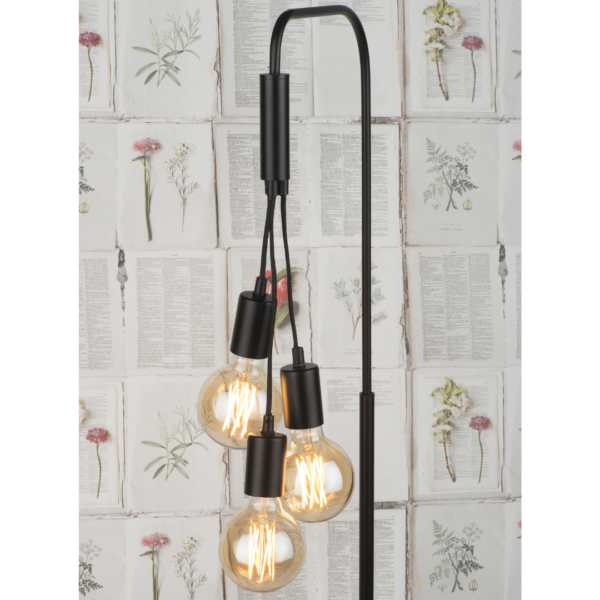 Ein Bild aus dem Taiga Store von taiga.green. Eine moderne schwarze Stehlampe mit vier freiliegenden Edison-Glühbirnen, die in verschiedenen Höhen hängen, vor einem Tapetenhintergrund mit botanischen Illustrationen und Textseiten. Jetzt bestellen im Eco Shop von www.taiga.green. Hier nachhaltig einkaufen mit dem Taiga Eco Rating