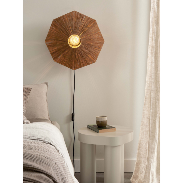 Ein Bild aus dem Taiga Store von taiga.green. Eine gemütliche Schlafzimmerszene mit einem Bett, einer strukturierten beigen Decke, einem runden weißen Nachttisch mit zwei Büchern und einer Tasse sowie einer an der Wand befestigten Sonnenbrillenlampe mit einem Holzschirm, die warm leuchtet. In der Nähe hängen hellbeige Vorhänge. Jetzt bestellen im Eco Shop von www.taiga.green. Hier nachhaltig einkaufen mit dem Taiga Eco Rating