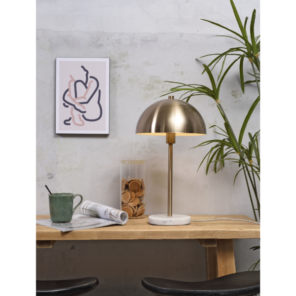 Ein Bild aus dem Taiga Store von taiga.green. Ein hölzerner Schreibtisch mit einer Messinglampe, einer grünen Tasse, einem Glas mit Keksen und einer zusammengerollten Zeitung. Eine Blattpflanze und abstrakte Kunst in einem weißen Rahmen stehen vor einer hellen, strukturierten Wand im Hintergrund. Jetzt bestellen im Eco Shop von www.taiga.green. Hier nachhaltig einkaufen mit dem Taiga Eco Rating