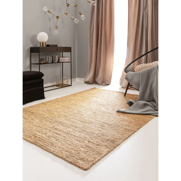 Ein Bild aus dem Taiga Store von taiga.green. Ein gemütliches, modernes Wohnzimmer mit einem natürlichen Webteppich, einem schwarzen Akzentsessel mit einer grauen Decke, einem schwarzen Konsolentisch mit einer Lampe und Dekoration, hellbeigen Vorhängen und einer einzigartigen goldenen Leuchte. Jetzt bestellen im Eco Shop von www.taiga.green. Hier nachhaltig einkaufen mit dem Taiga Eco Rating