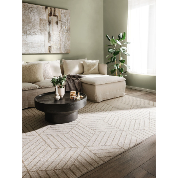 Ein Bild aus dem Taiga Store von taiga.green. Ein modernes Wohnzimmer mit einem beigen Sektionssofa, einem schwarzen runden Couchtisch, einem geometrisch gemusterten Teppich, einer Topfpflanze, abstrakter Wandkunst und Sonnenlicht, das durch ein Fenster mit weißen Vorhängen fällt. Jetzt bestellen im Eco Shop von www.taiga.green. Hier nachhaltig einkaufen mit dem Taiga Eco Rating