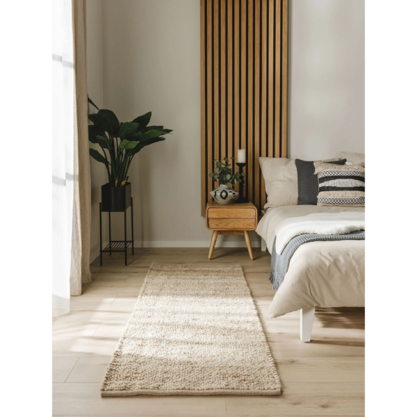 Ein Bild aus dem Taiga Store von taiga.green. Ein modernes Schlafzimmer verfügt über einen beigen Teppichläufer auf hellem Holzboden, ein ordentlich gemachtes Bett mit gemusterten Kissen, einen hölzernen Nachttisch mit Dekoration, eine Topfpflanze und eine Akzentwand aus Lattenholz. Der Raum ist von natürlichem Licht durchflutet. Jetzt bestellen im Eco Shop von www.taiga.green. Hier nachhaltig einkaufen mit dem Taiga Eco Rating