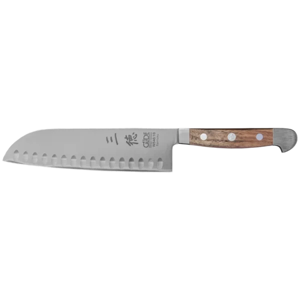 Ein Bild aus dem Taiga Store von taiga.green. Ein Santoku-Küchenmesser aus rostfreiem Stahl mit einem Holzgriff und Nieten. Die Klinge hat eine Reihe von Vertiefungen entlang der Kante und ist mit japanischen Schriftzeichen und einem Brandzeichen in der Nähe des Griffs versehen. Jetzt bestellen im Eco Shop von www.taiga.green. Hier nachhaltig einkaufen mit dem Taiga Eco Rating